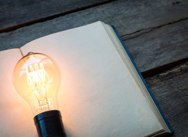 lit light bulb on top of book