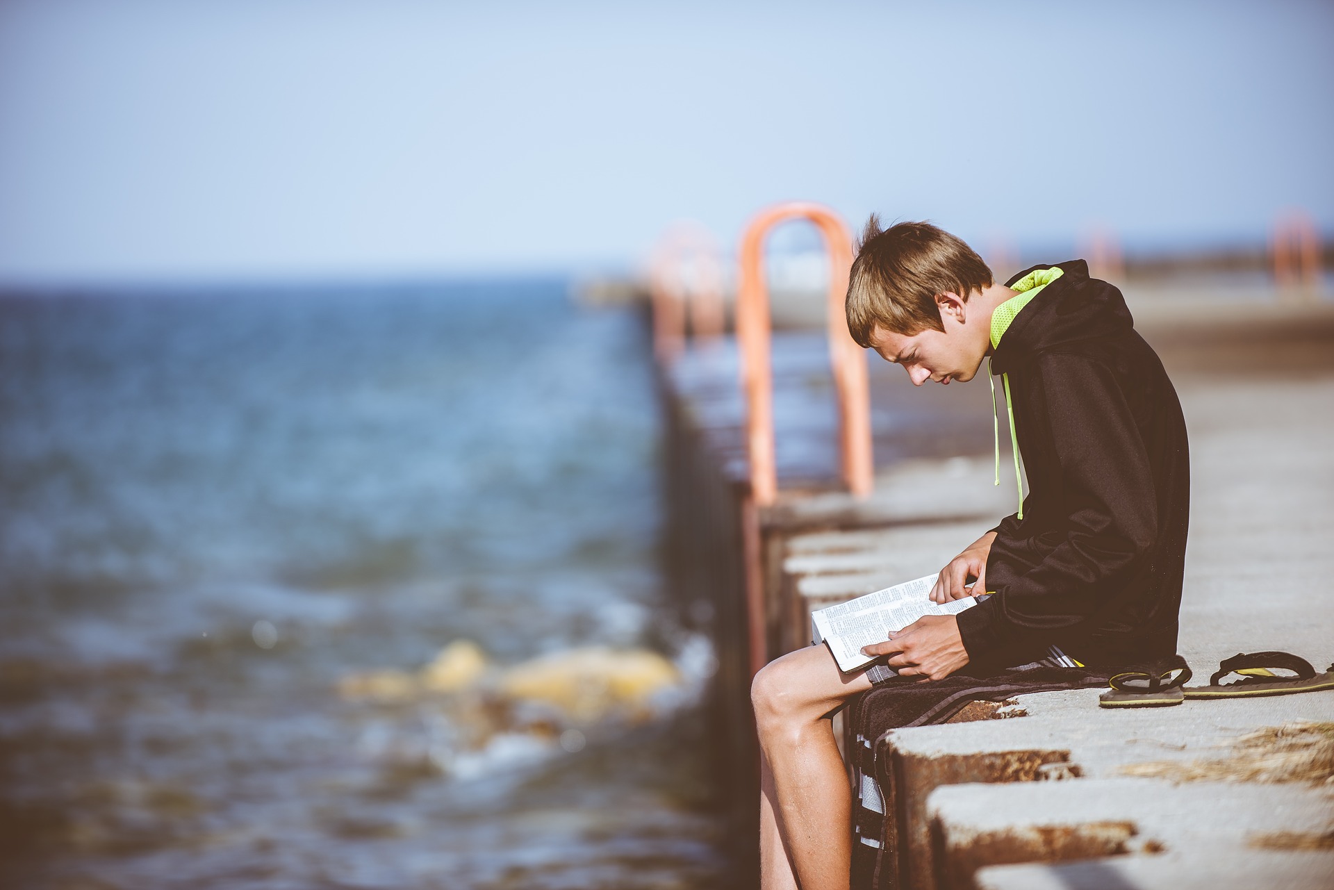 boy sitting on edge of dock reading