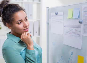 woman looking at notes and data posted on board