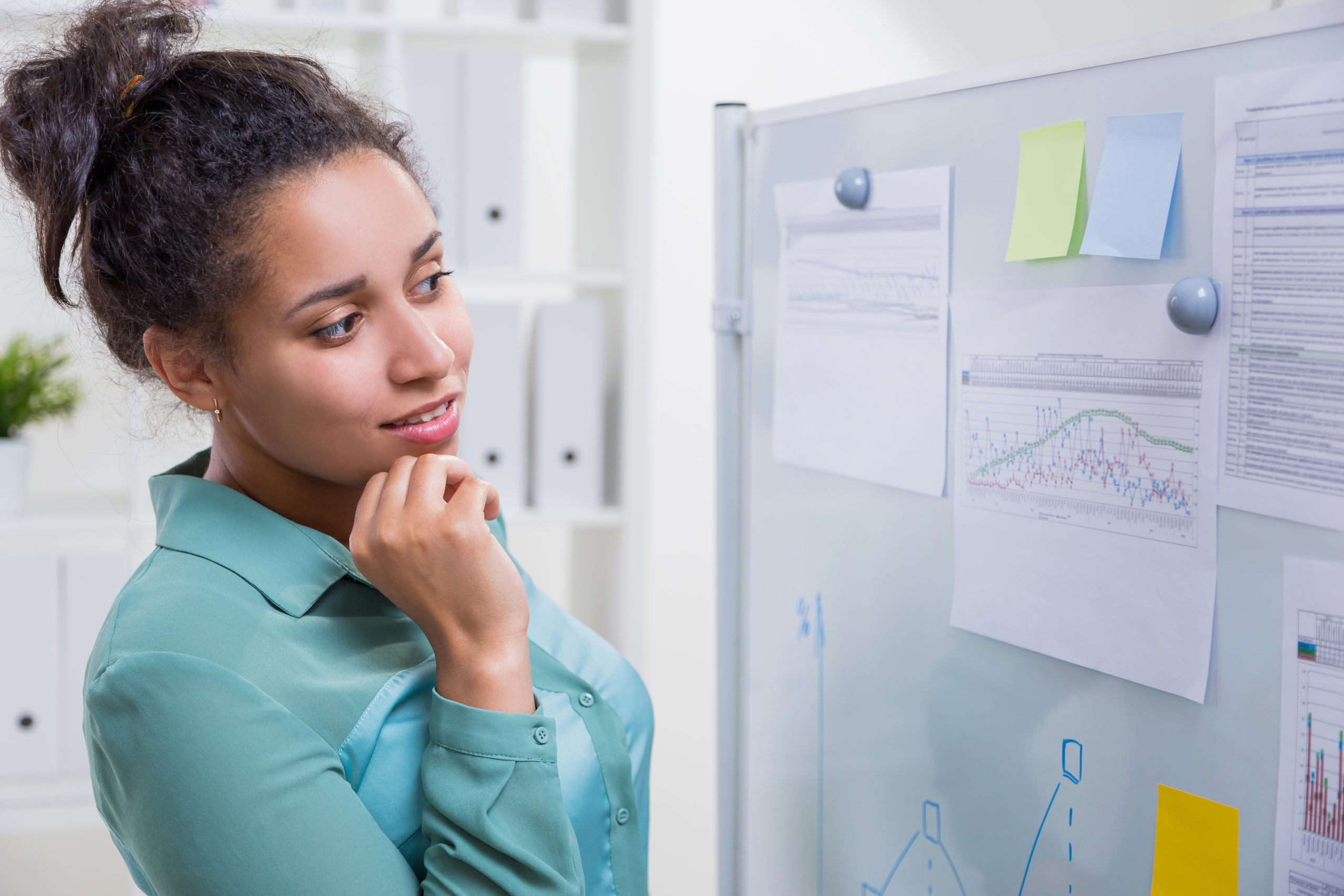 woman looking at notes and data posted on board