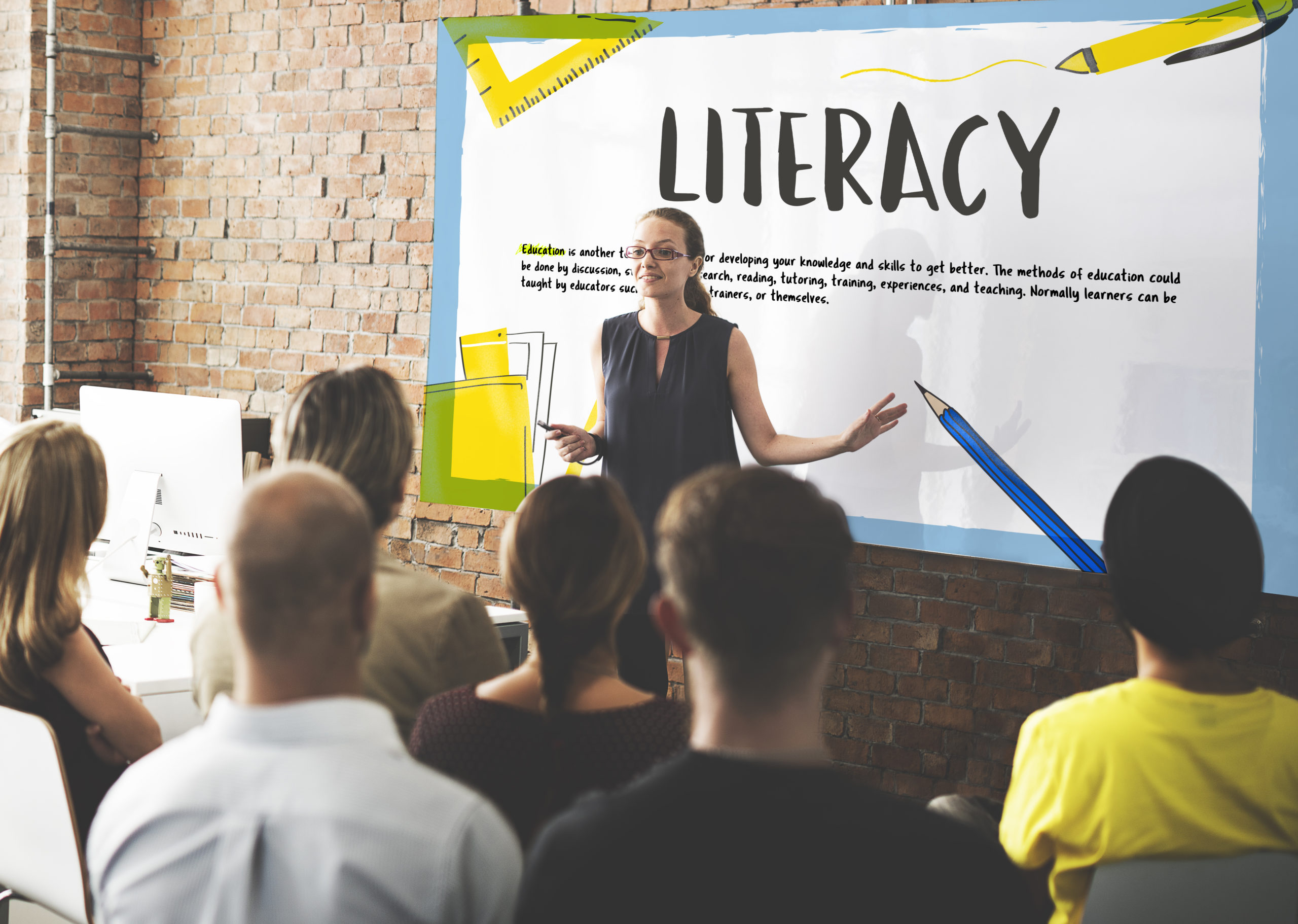 woman presenting in front of board with big literacy heading