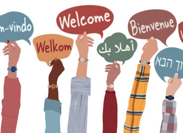 Hands holding up welcome signs in different languages